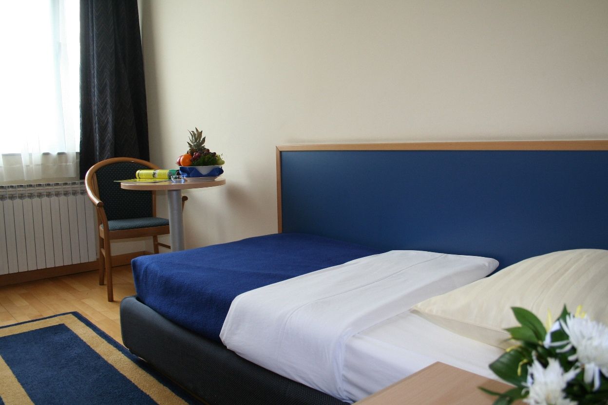 Made-up single bed with fruit and table by the window